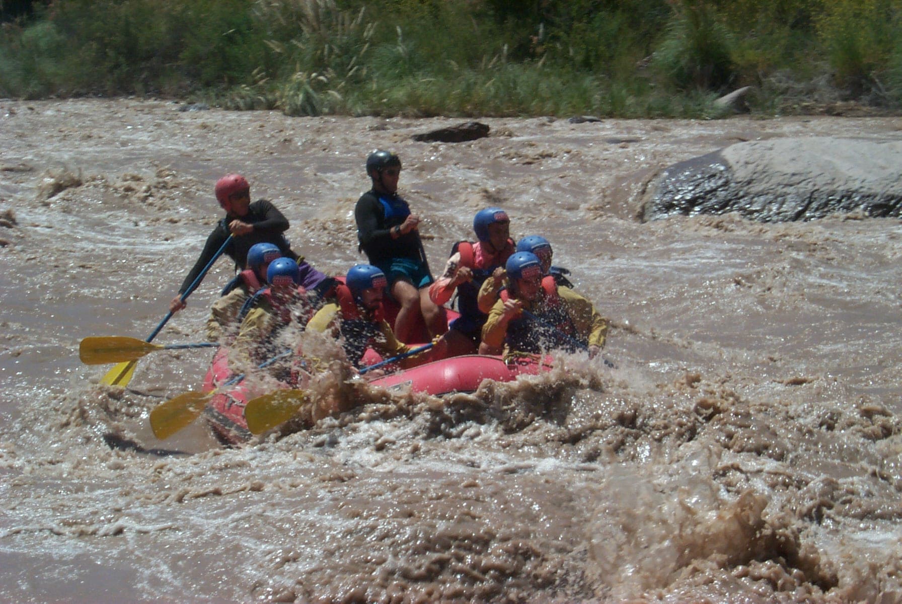 Gomón de rafting con remeros con casco en los rápidos del río Mendoza