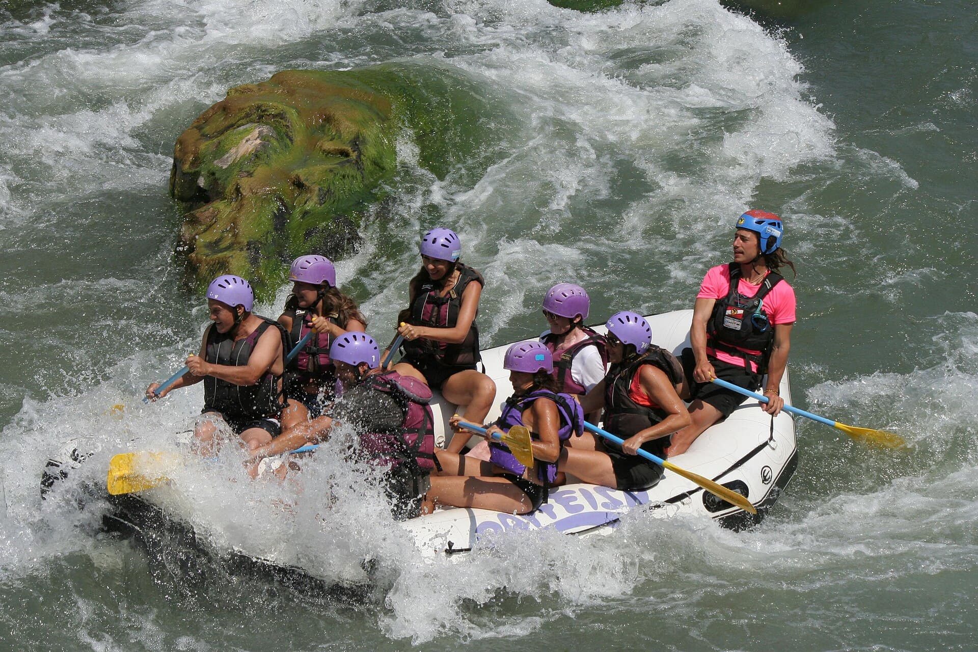 Grupo con cascos y chalecos en un gomón, en los rápidos del río Atuel